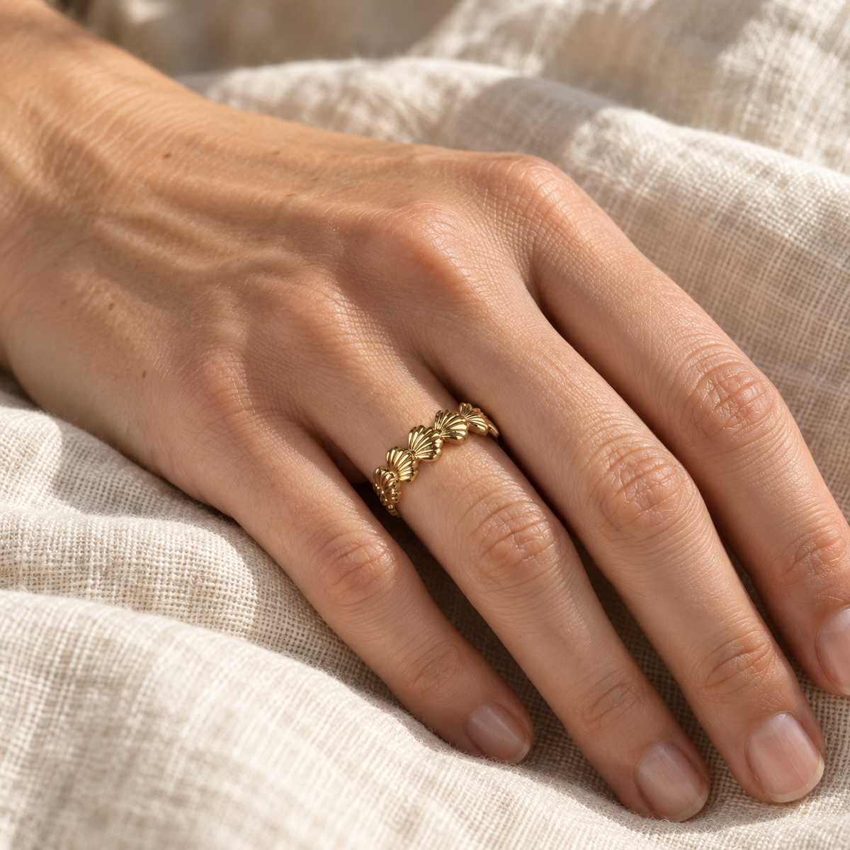 Lucia Muschelring an einer Hand auf hellem Leinen